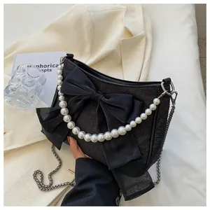 Dettaglio borsa nera plissettata con grande fiocco, manico di perle e catena d'argento