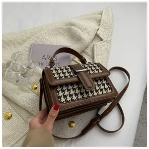Borsa a tracolla in pelle marrone e pied-de-poule su sfondo di giacca di tweed bianco