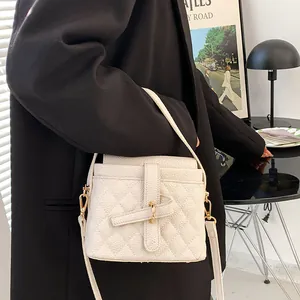 Elegante borsa bianca sfumata con dettagli dorati mostrata su un outfit moderno da modella
