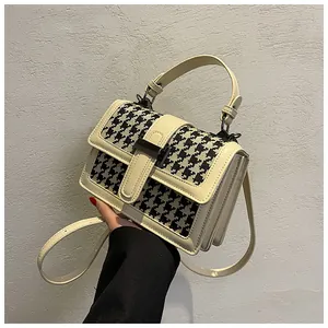 Dettagli del manico in pelle crema e del motivo pied-de-poule di una borsa a tracolla