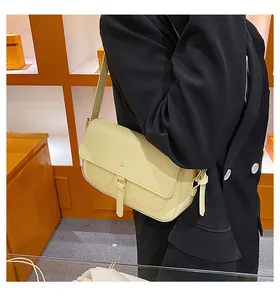 Dettaglio della borsa a spalla in pelle giallo pallido con patta e tracolla su modella