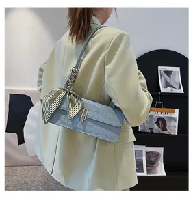 Dettaglio borsa azzurra texture coccodrillo con foulard di seta a righe verdi