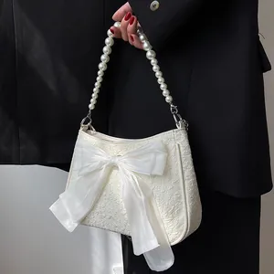 Borsa a tracolla bianca testurizzata con fiocco grande e manico di perle indossata