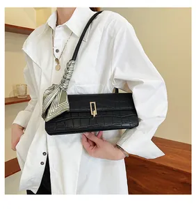 Dettaglio borsa nera motivo coccodrillo con fibbia dorata e tracolla decorata con foulard
