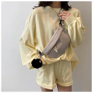 Dettaglio della borsa a tracolla beige in nylon con ciondolo di peluche nero