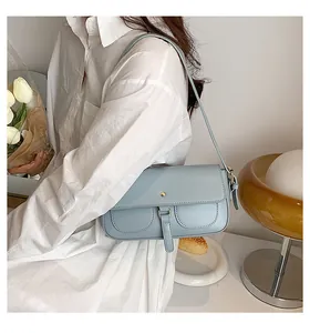 Borsa sottobraccio azzurra in ecopelle su modella con dettagli di fibbie e tracolla sottile