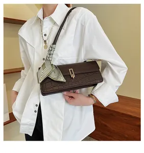 Dettaglio borsa marrone scuro con trama a coccodrillo fibbia dorata e foulard di seta