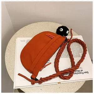 Dettaglio della borsa a mezzaluna arancione in tela con tracolla in corda e ciondolo plush