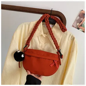 Dettaglio della borsa a mezzaluna in tela rosso mattone con tracolla in corda intrecciata