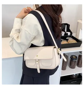 Dettaglio di una borsa baguette color crema con fibbie decorative in un ambiente da caffè