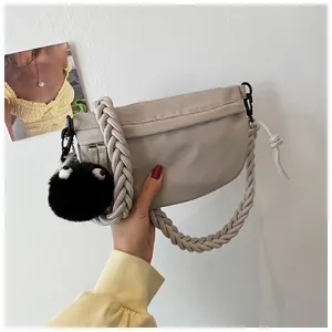 Dettaglio borsa beige a mezzaluna con tracolla in corda intrecciata e ciondolo di peluche