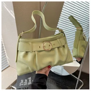 Dettaglio della borsa a pieghe verde chiaro con fibbia circolare dorata e ombre delicate