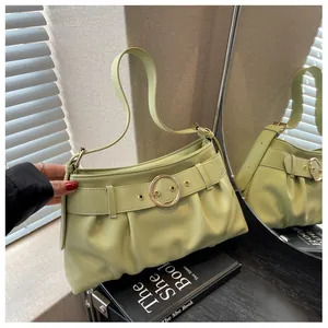 Dettaglio della borsa sottobraccio a pieghe verde chiaro con fibbia dorata e finitura in pelle