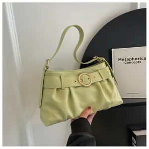 Dettaglio della borsa a pieghe verde pistacchio con elegante fibbia rotonda dorata