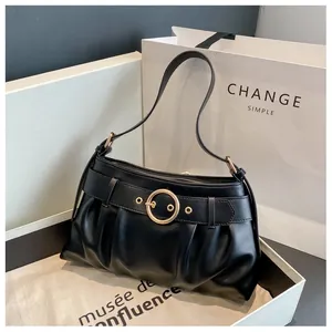 Dettaglio della borsa a spalla nera con fibbia rotonda dorata e cinturino decorativo