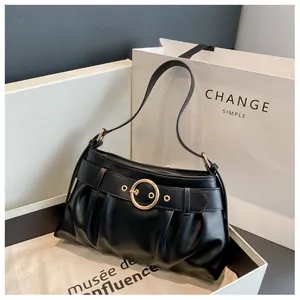Dettaglio della borsa a spalla nera a pieghe con una grande fibbia decorativa in metallo oro