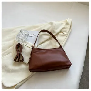 Dettaglio borsa a nuvola plissettata marrone su blazer beige con tracolla lunga