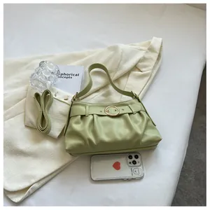 Dettaglio borsa baguette plissettata verde avocado con fibbia dorata e tracolla