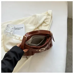 Dettaglio interno della borsa a tracolla marrone plissettata con tasca a zip e fibbia in metallo