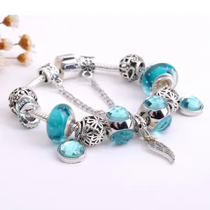 Bracciale in argento S925 con perle di vetro blu e ciondolo a piuma su sfondo bianco
