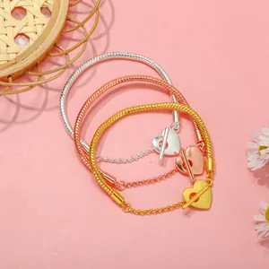 Dettaglio di bracciali a serpente in argento, oro e oro rosa con chiusura a T a cuore