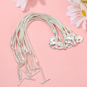 Dettaglio di bracciali a catena serpente argento con ciondoli a cuore e chiusura T-bar