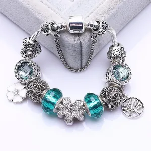 Silver charm bracelet with blue glass beads, tree of life and floral pendants