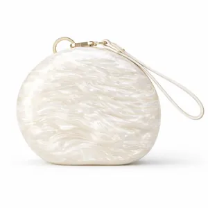 Detail of pearlescent marble acrylic evening clutch with gold ring hardware and wrist strap