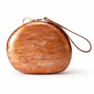 Detail of amber marble acrylic clutch with gold hardware and brown leather wrist strap