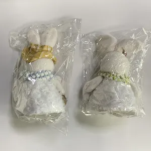 Close-up of Easter plush bunny dolls in packaging with lace skirts and woven collars