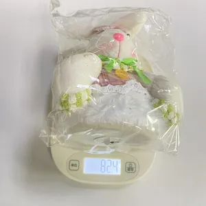 Close-up of a plush Easter bunny in pink dress being weighed on a digital scale