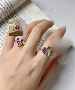 Détail des bagues en argent S925 en forme de cœur avec zircon rose sur fond de livre