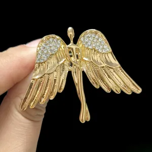 Detailed view of hand-held gold angel wing brooch with sparkling diamond crystals