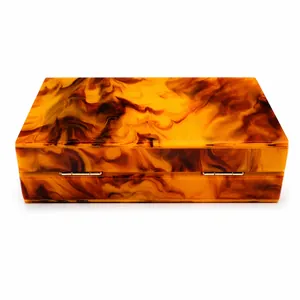 Vista dettagliata della pochette in acrilico con motivo marmo ambra e cerniere d'oro.