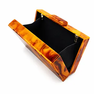 Vista dettagliata della pochette in acrilico ambrato con interno in tessuto nero.