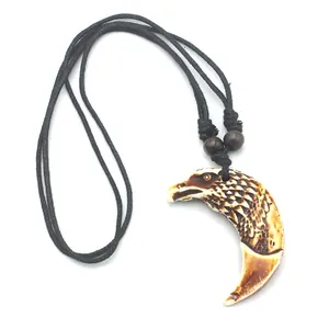 Détail de la sculpture de tête d'aigle sur pendentif tribal avec cordon tressé