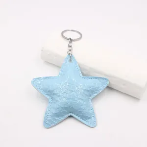 Macro view of light blue star-shaped leather keychain with embossed texture and silver ring