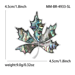 Elegant maple leaf brooch with colorful shell inlay and silver metal frame on white background