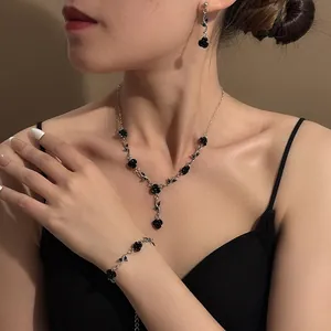 Model wearing black rose jewelry set with necklace, earrings, and bracelet detail