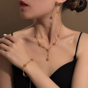 Elegant macro view of a vintage golden rose jewelry set worn by a model in soft lighting