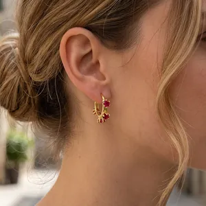 Detail of 18K gold flower hoop earrings with red zircon stones on a model