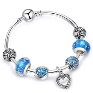Dettaglio di bracciale con ciondoli argentato, perle di vetro blu e pendente a cuore