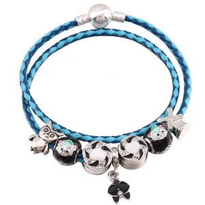 Dettaglio del bracciale in pelle blu bicolore con ciondoli argentati a gufo e panda