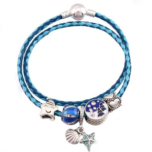 Dettaglio del bracciale in pelle intrecciata blu con ciondoli a stella e marina