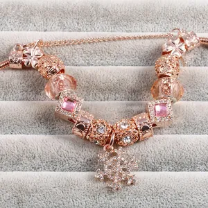 Detail of rose gold charm bracelet with snowflake pendant and pink crystal beads