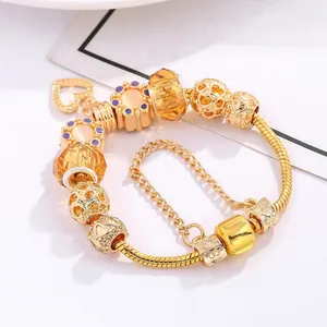 Macro view of gold charm bracelet with heart pendant, glass beads and snake chain