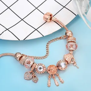 Pulsera de oro rosa con dijes de atrapasueños corazón y llave en una cadena de serpiente