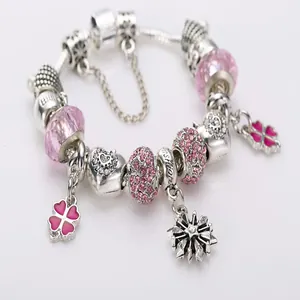 Silver snake chain bracelet with pink crystal beads and clover charms on white background