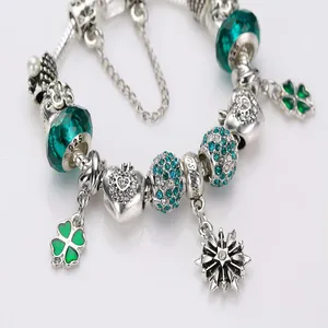 Macro detail of silver DIY charm bracelet with green beads and clover pendant charms