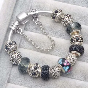 Dettaglio macro del bracciale con ciondoli in argento e perline floreali su velluto
